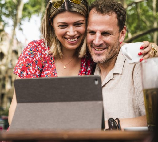 Smiling couple sharing tablet at an outdoor cafe